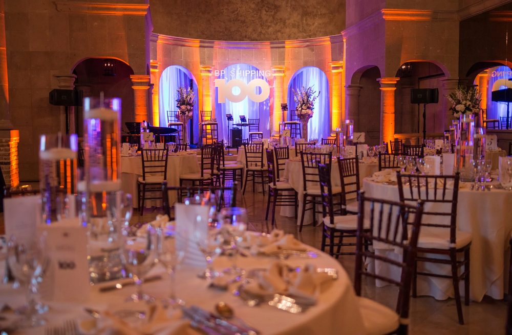 Anniversary banquet with tall glass centerpieces and a branded stage in the ballroom at The Bell Tower on 34th, Houston, TX.